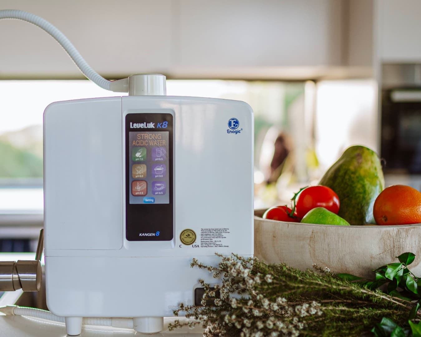 Enagic Leveluk K8 water ionizer on a kitchen counter, touchscreen displaying seven water settings including 9.5 pH alkaline and 2.5 pH strong acidic
